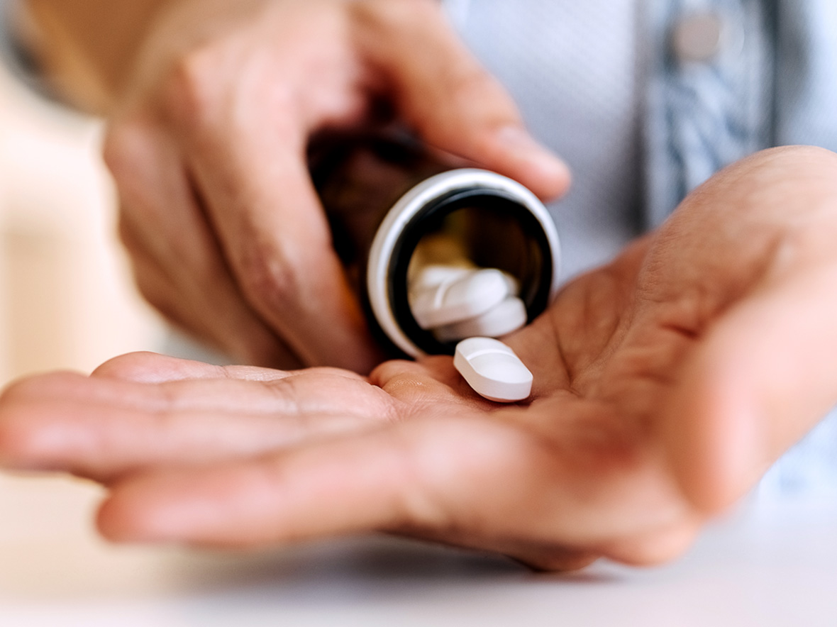 Close up of person pouring prescription pills into hand